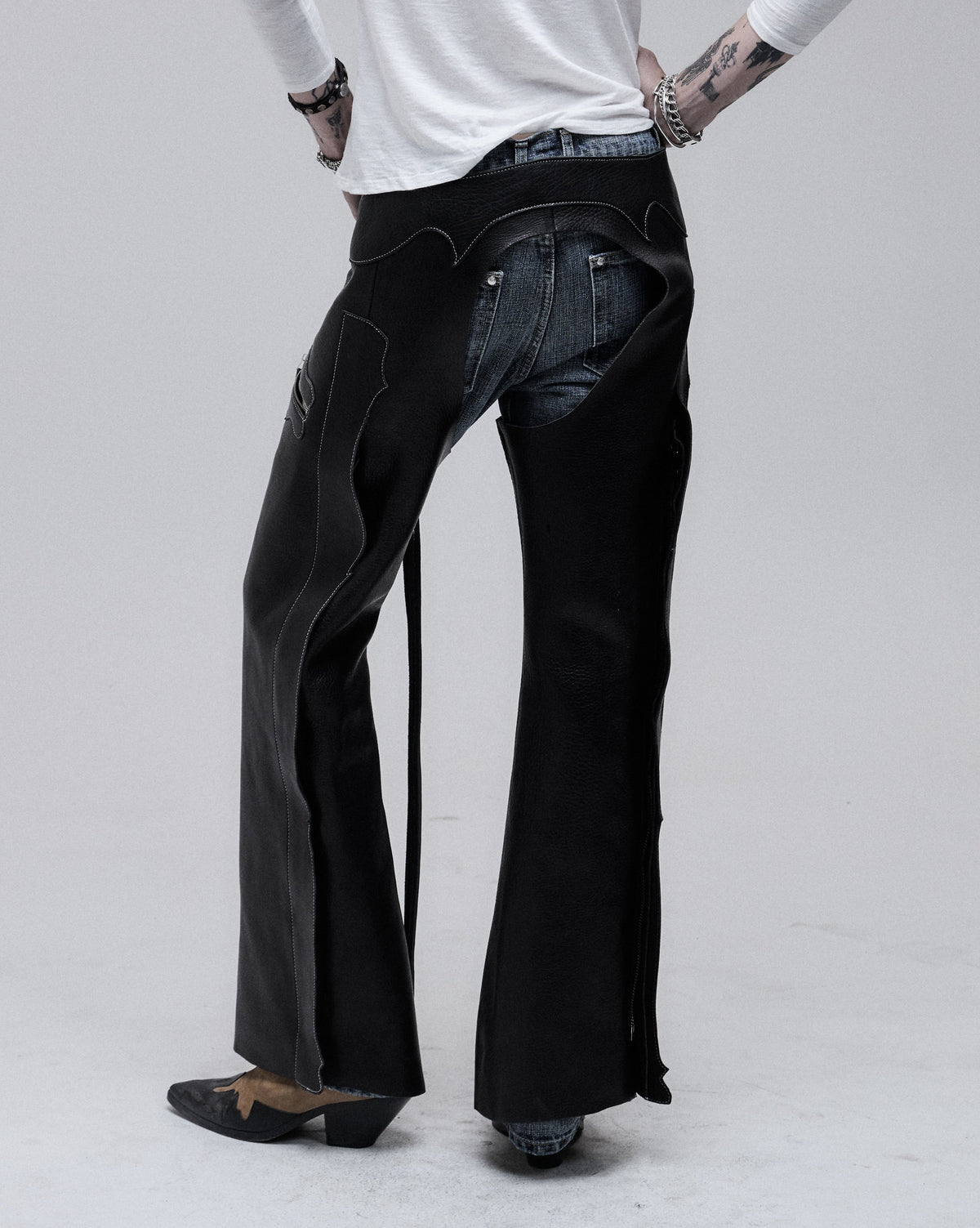 Riding Chaps in black leather, back view on model, worn over jeans