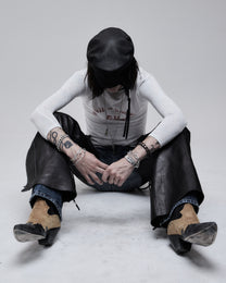 Riding Chaps in black leather, worn by a seated model