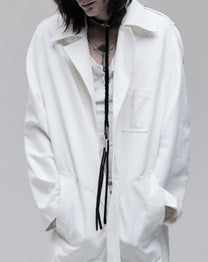 Tassel necklace in black leather and silver, worn loose over a white shirt